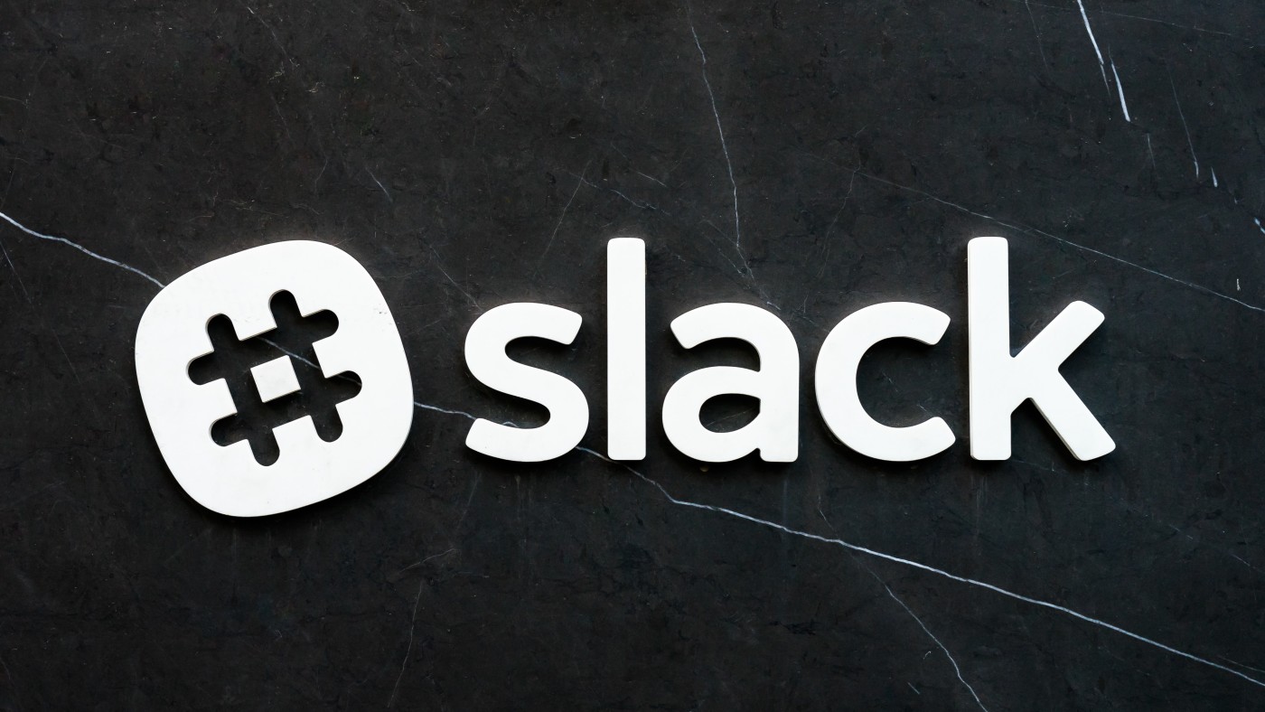 The Slack logo in white lettering on a dark marble wall.